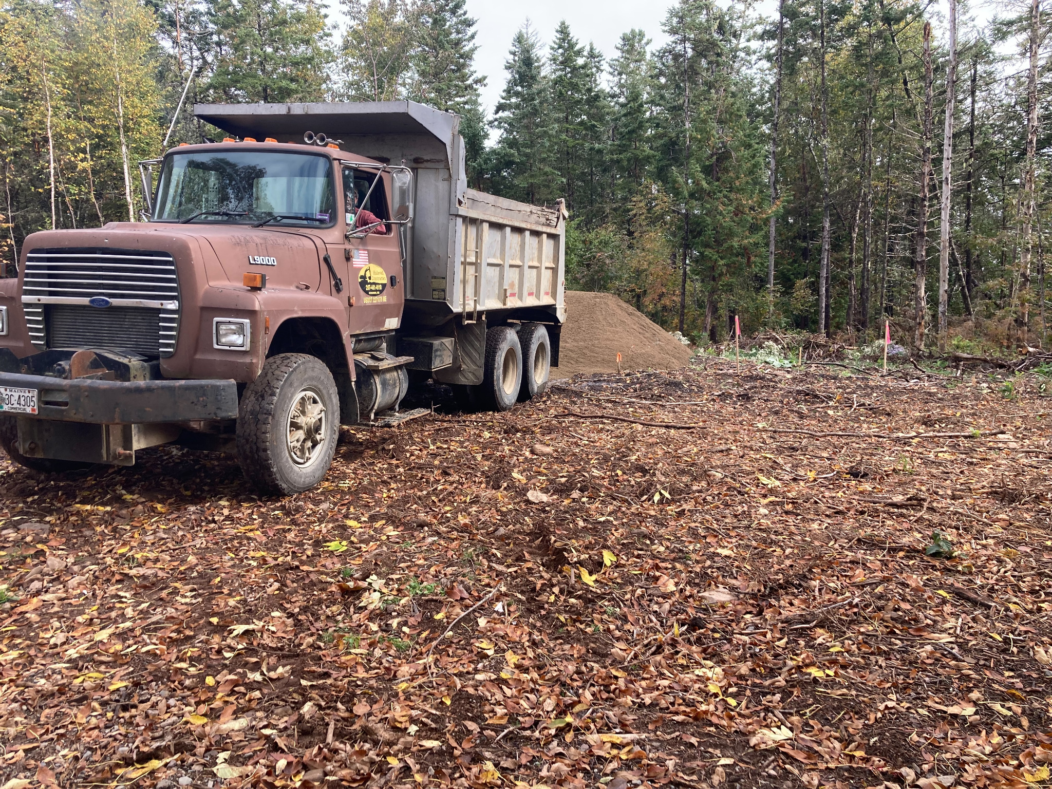 Hallowell Construction dump truck at a wooded job site in Maine